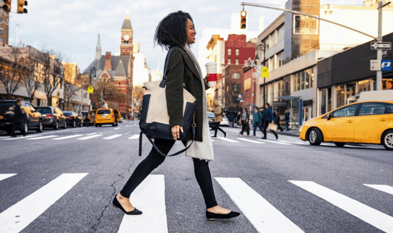 Woman crossing a city street at a crosswalk with traffic nearby – legal services for pedestrian accident victims in Connecticut.