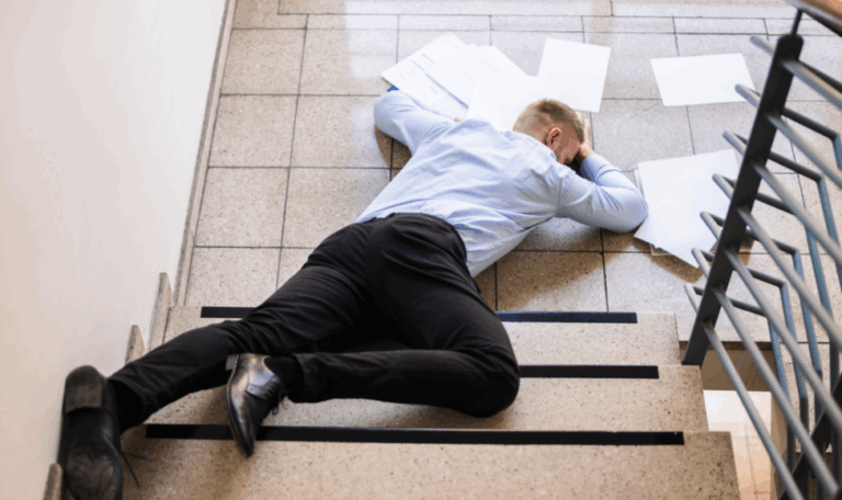 lying face down at the bottom of a stairwell with scattered papers after a fall, representing a slip and fall injury in Connecticut