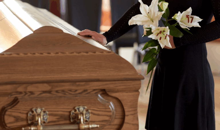Woman in black dress holding white lilies at a wooden casket during a funeral, symbolizing a wrongful death case in Connecticut