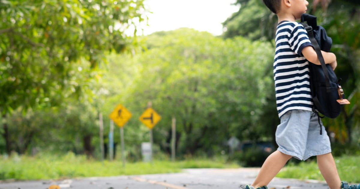 Child crossing road near school zone with traffic signs – school injury lawyer Connecticut